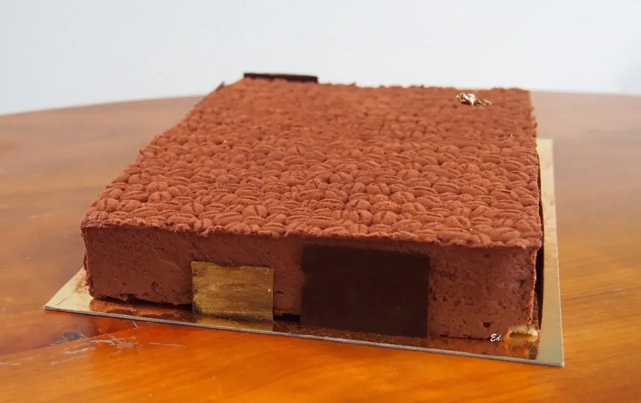 Gâteau rectangulaire au chocolat, décoré d'une texture rappelant des grains de café. Une recette insert crémeux café à savourer.