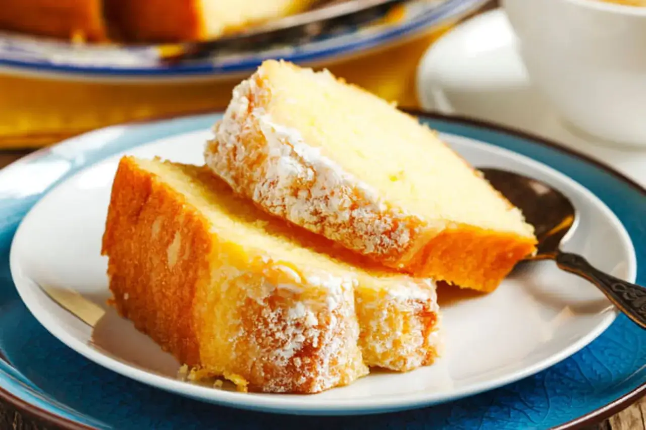 Deux parts de gâteau au yaourt, saupoudrées de sucre glace, sur une assiette blanche. Une recette illustrée facile à réaliser.