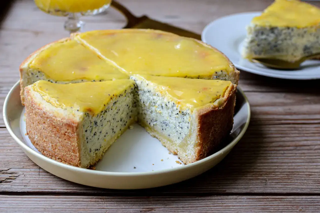 Un délicieux gâteau pavot allemand, avec une garniture jaune vif, est coupé en parts sur une assiette.