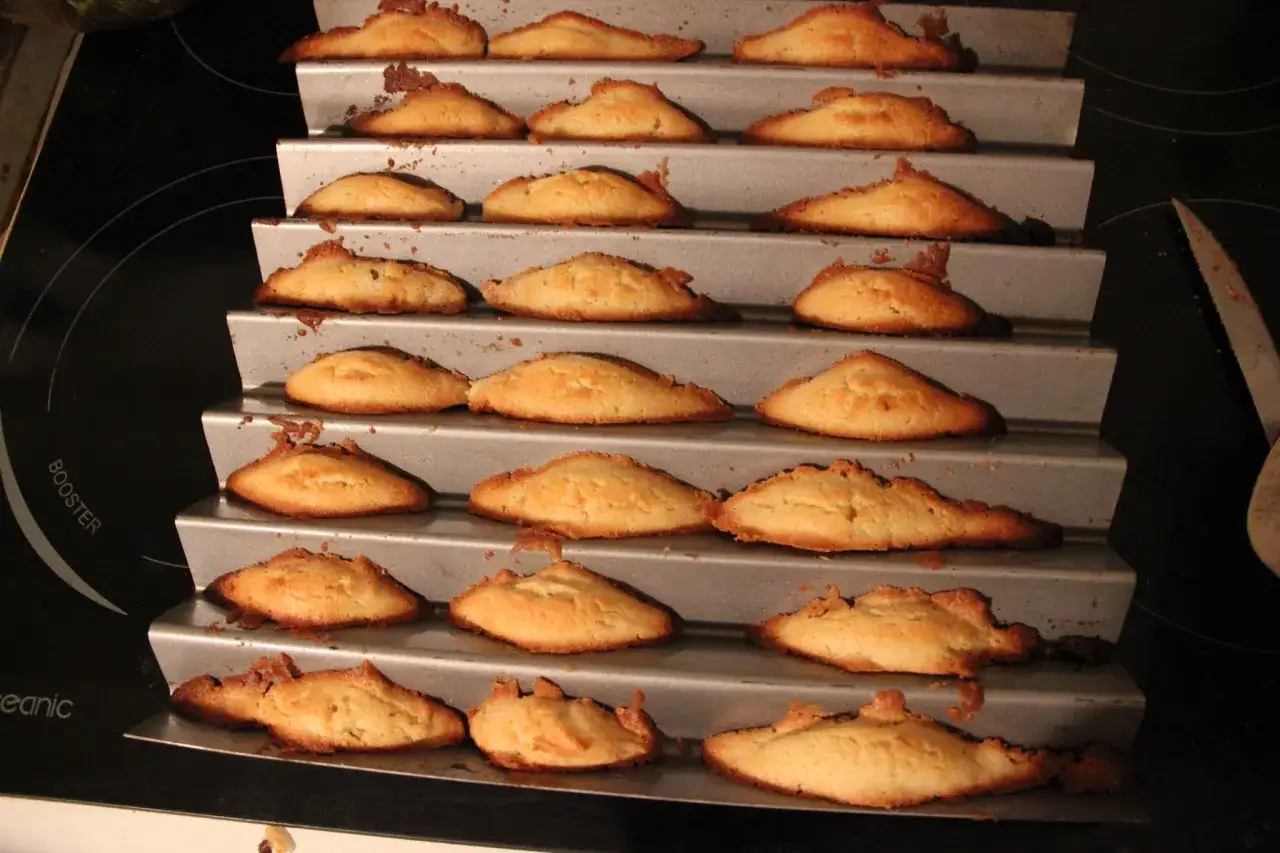 Des biscuits dorés, certains ressemblant à une dent de loup, sortent d'un moule à plusieurs niveaux.