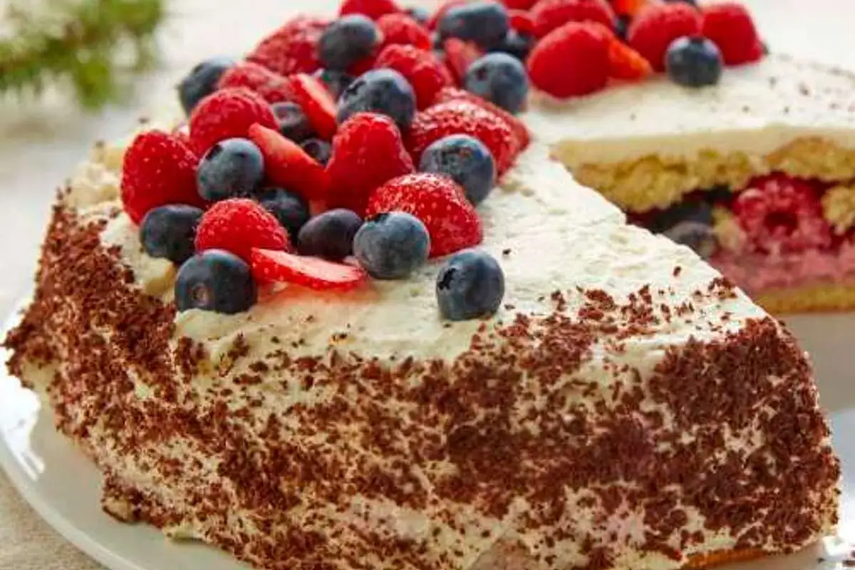 Gâteau aux fruits rouges et crème fouettée pour gâteau, décoré de copeaux de chocolat.