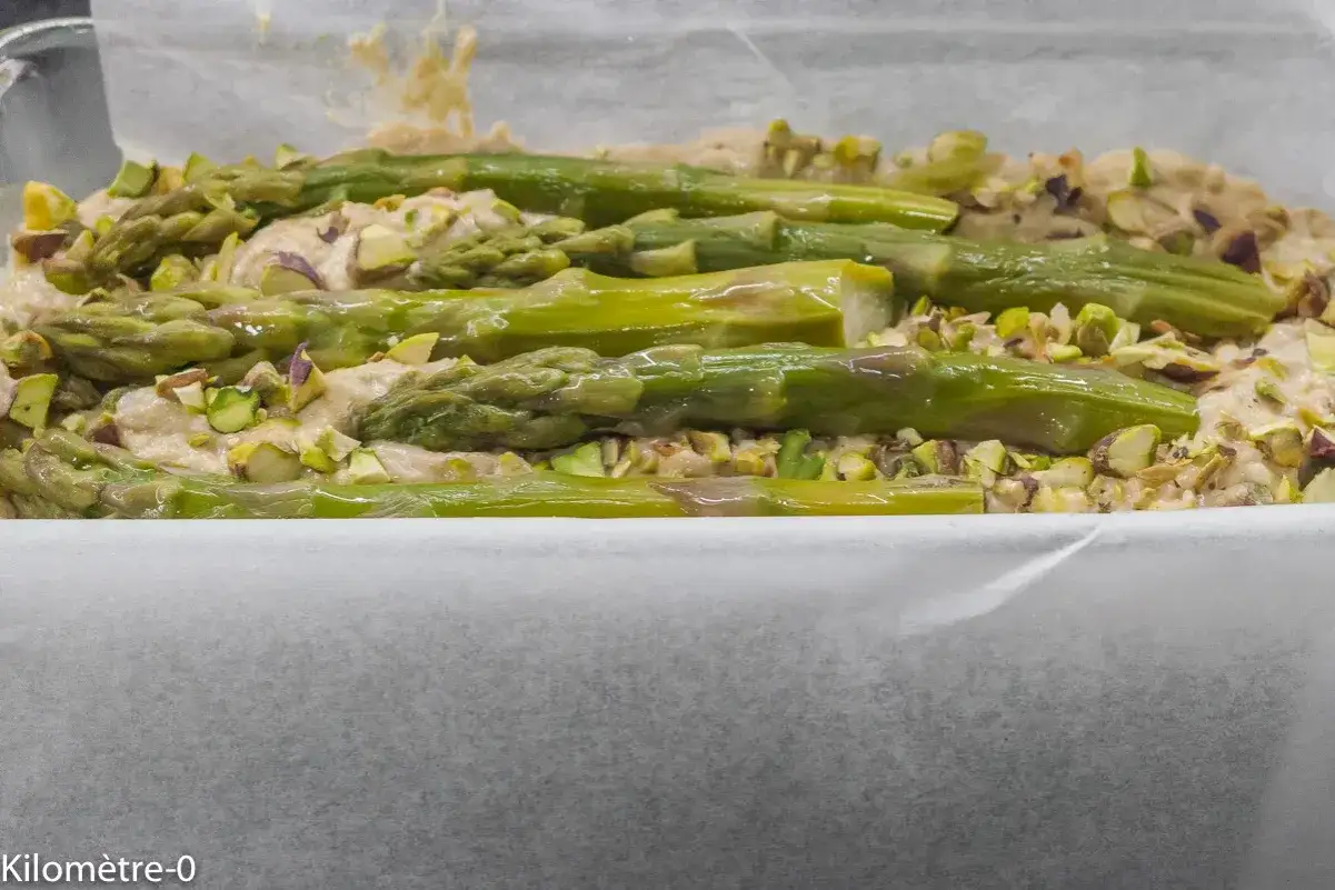 Préparation d'un plat savoureux avec des asperges vertes fraîches et des pistaches concassées, parfait pour la saison.