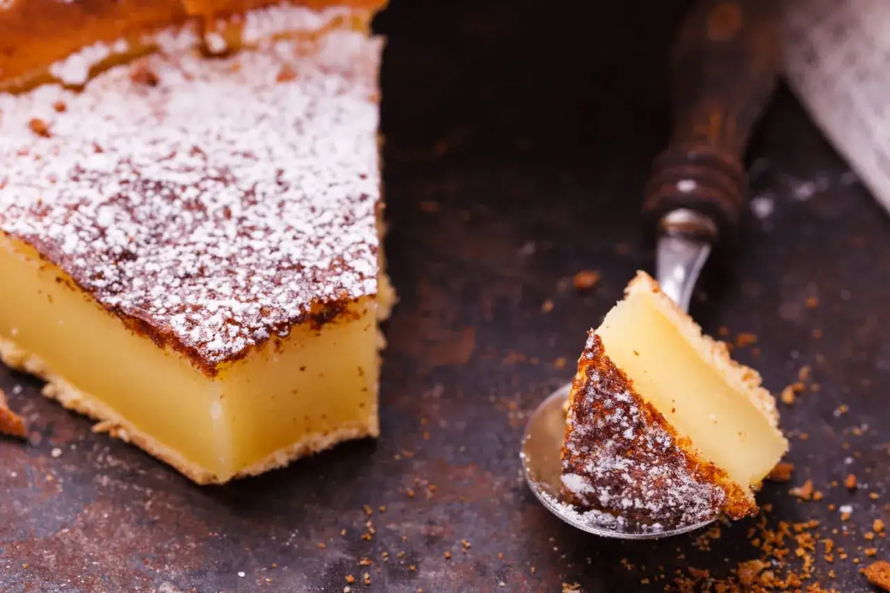 Tranche de flan pâtissier saupoudrée de sucre glace, prête à être dégustée. La cuisson flan pâtissier chaleur tournante ou pas, le résultat est toujours aussi gourmand.
