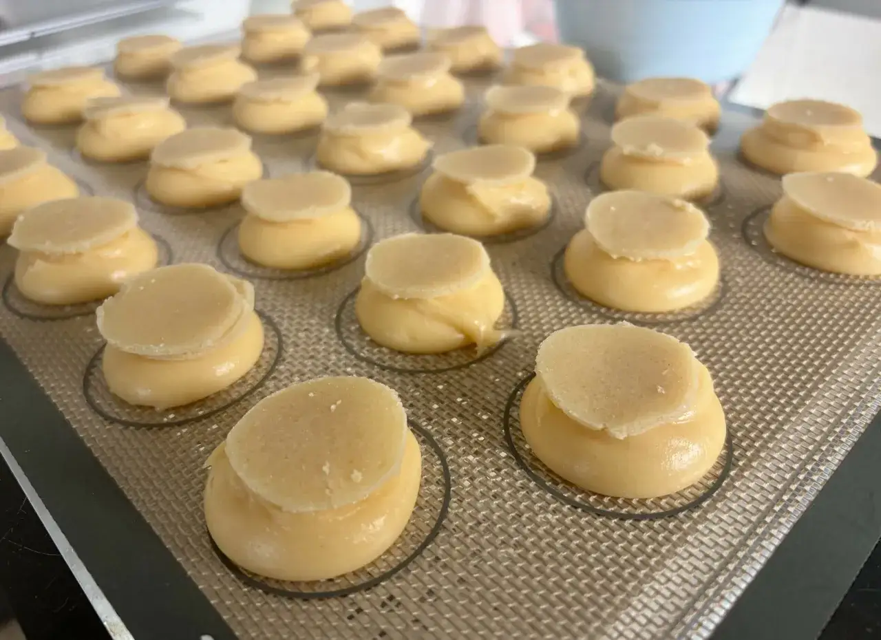 Des petits choux pâtissiers prêts à être cuits, avec leur chapeau de pâte sablée. Une gourmandise en devenir.