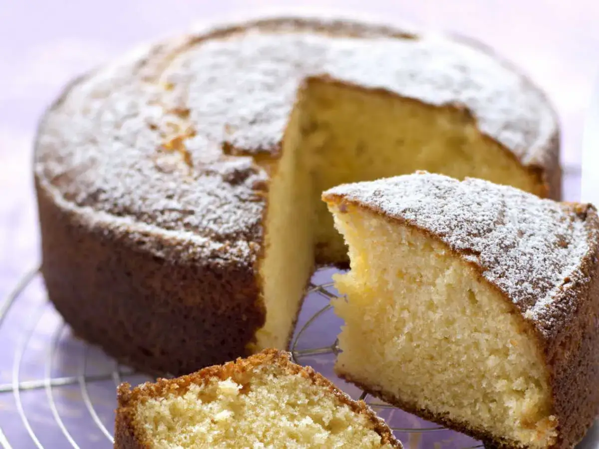 Un gâteau moelleux sans oeuf, saupoudré de sucre glace, avec une part coupée. Parfait pour un goûter gourmand.