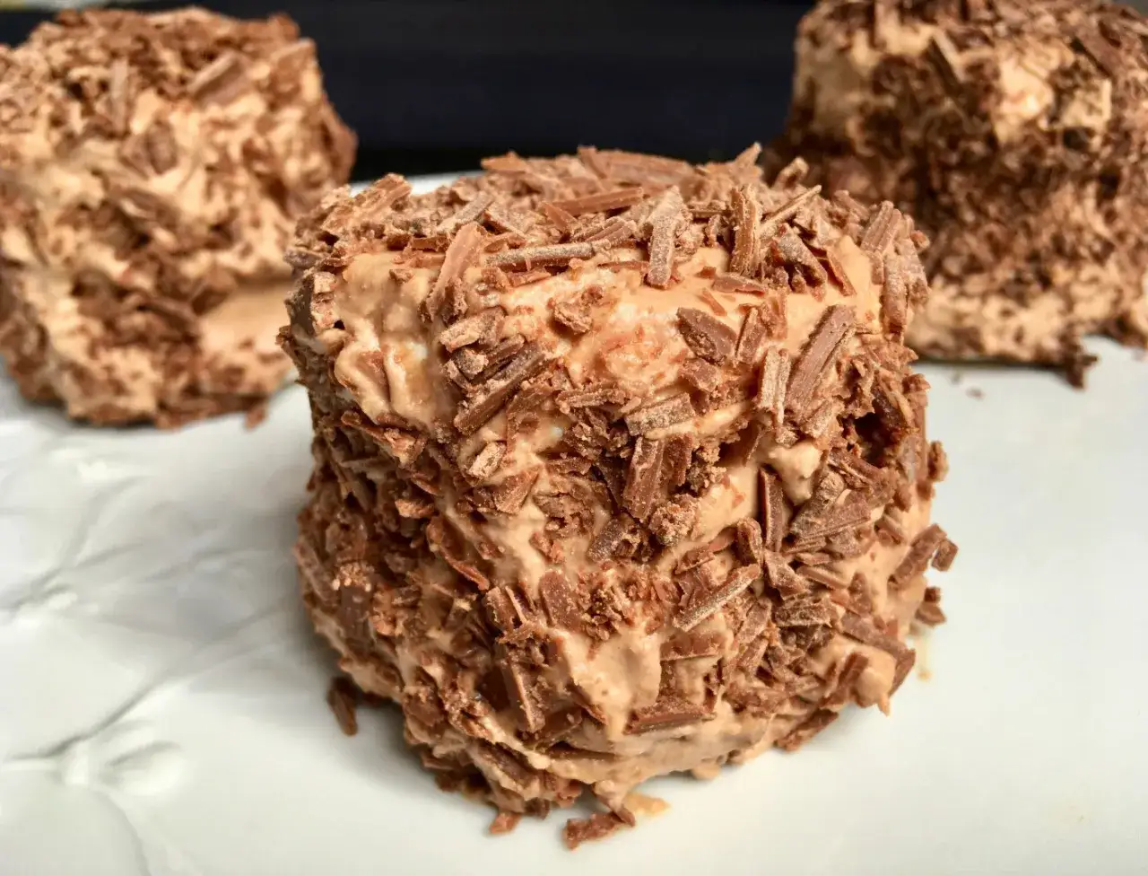 Gâteaux individuels recouverts de copeaux de chocolat, faits avec de la crème fraîche à fouetter pour une texture aérienne.