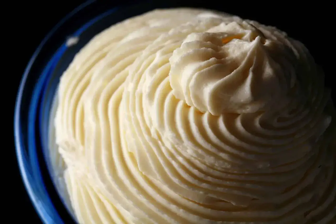 Ganache chocolat blanc onctueuse, dressée en spirales dans un bol bleu. Une texture douce et invitante.