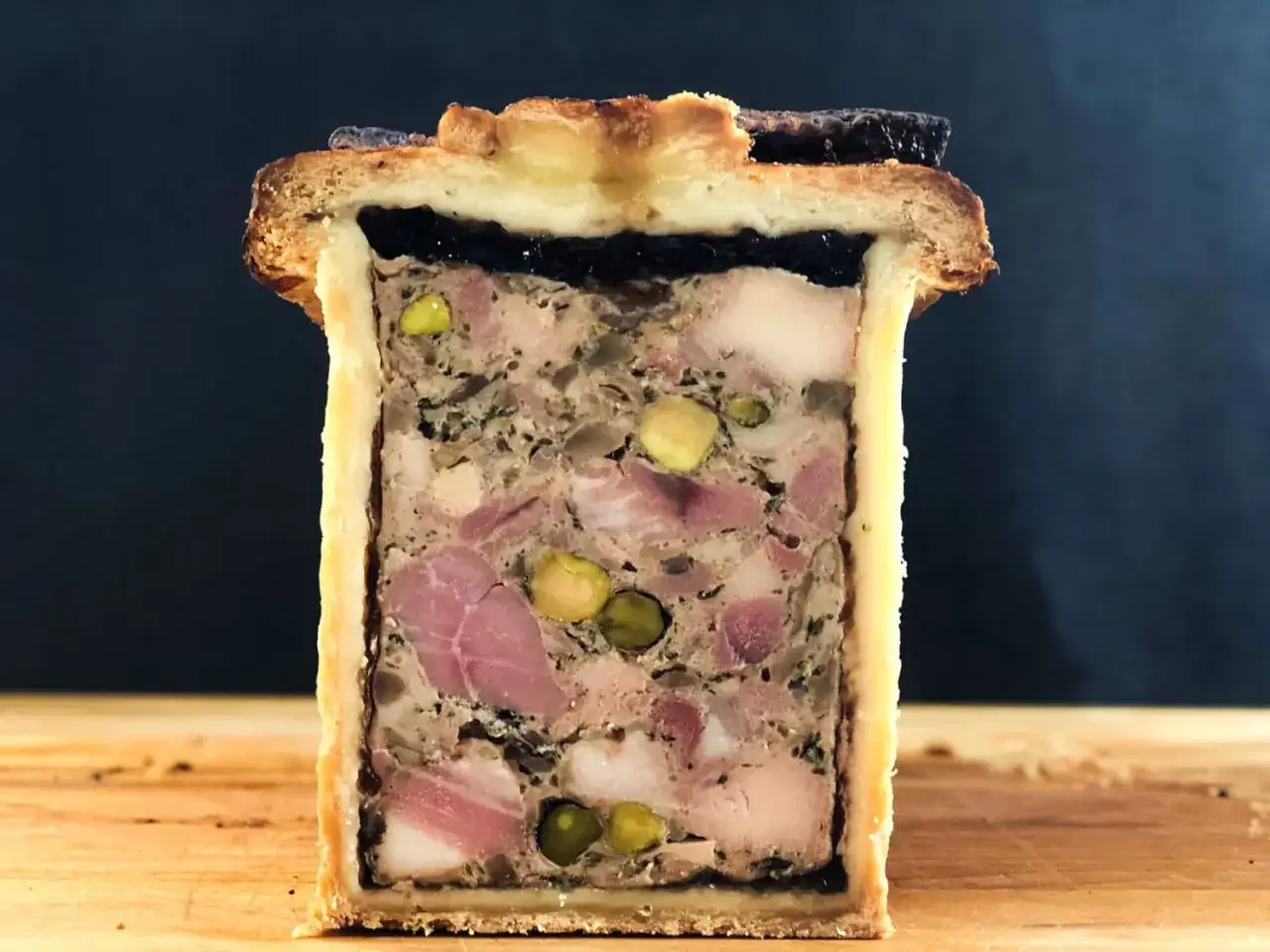 Pâté en croûte aux pistaches et fruits secs, une tranche parfaite pour la recette du meilleur pâté en croûte du monde.