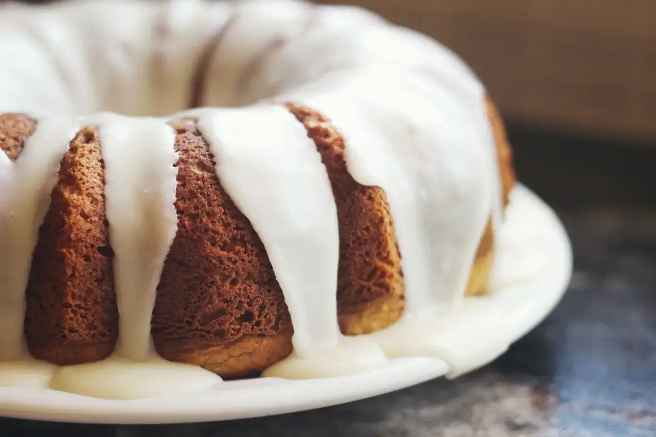 G&acirc;teau moul&eacute;, brun dor&eacute;, g&eacute;n&eacute;reusement napp&eacute; d'un fondant blanc cr&eacute;meux qui coule sur les c&ocirc;t&eacute;s.