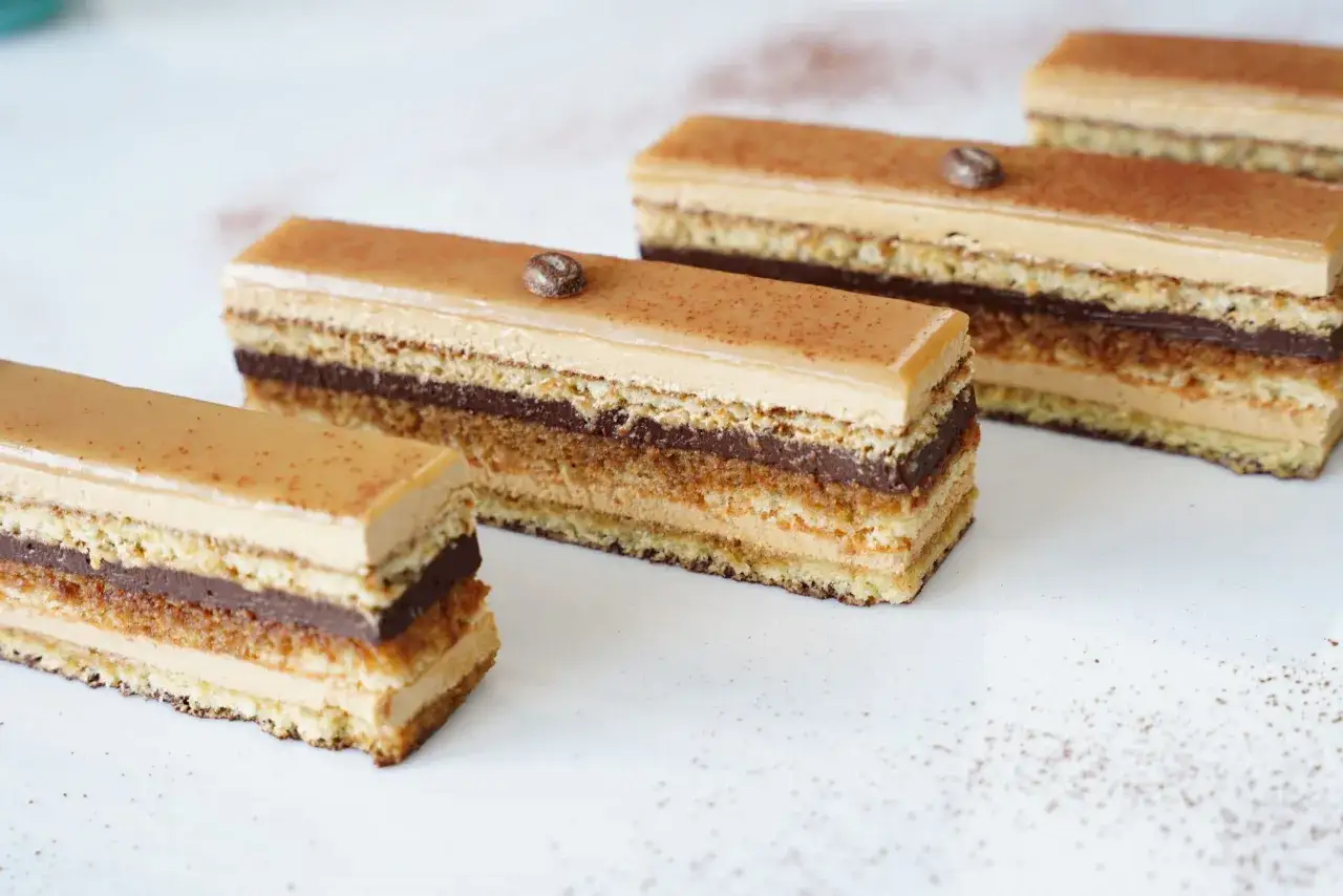 Délicieux gâteaux Opéra, une recette facile pour un dessert gourmand. Ils sont garnis de couches de biscuit Joconde, crème au beurre café, ganache chocolat et glaçage miroir.