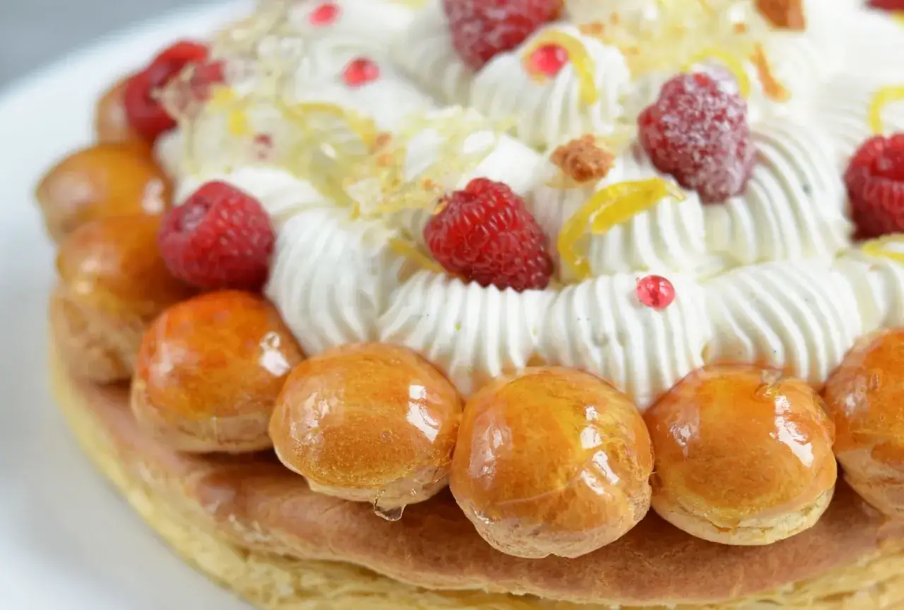 Un délicieux saint honoré framboise, garni de crème fouettée, de fruits rouges et de petites brioches caramélisées.