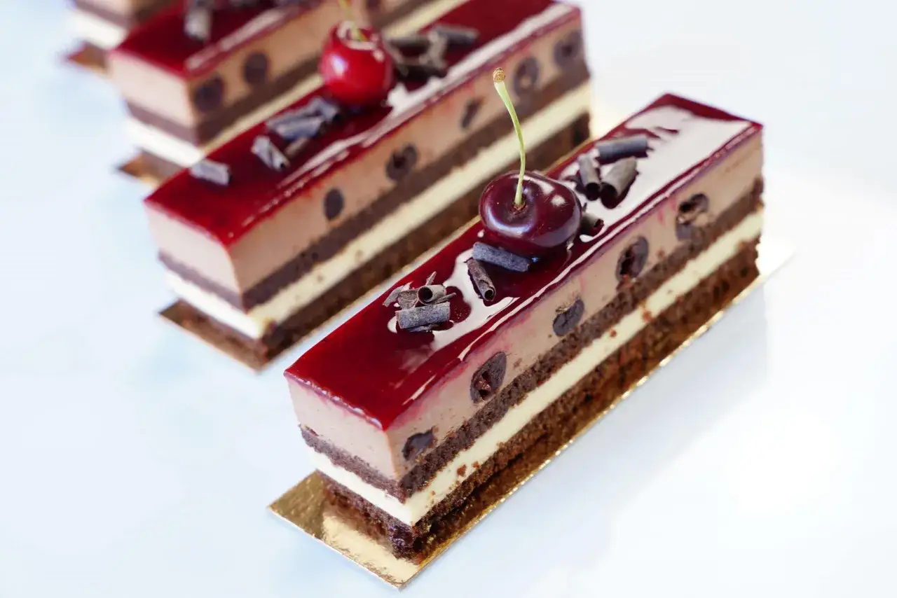 Pâtisseries individuelles, version professionnelle de la recette forêt noire, avec cerises et copeaux de chocolat.