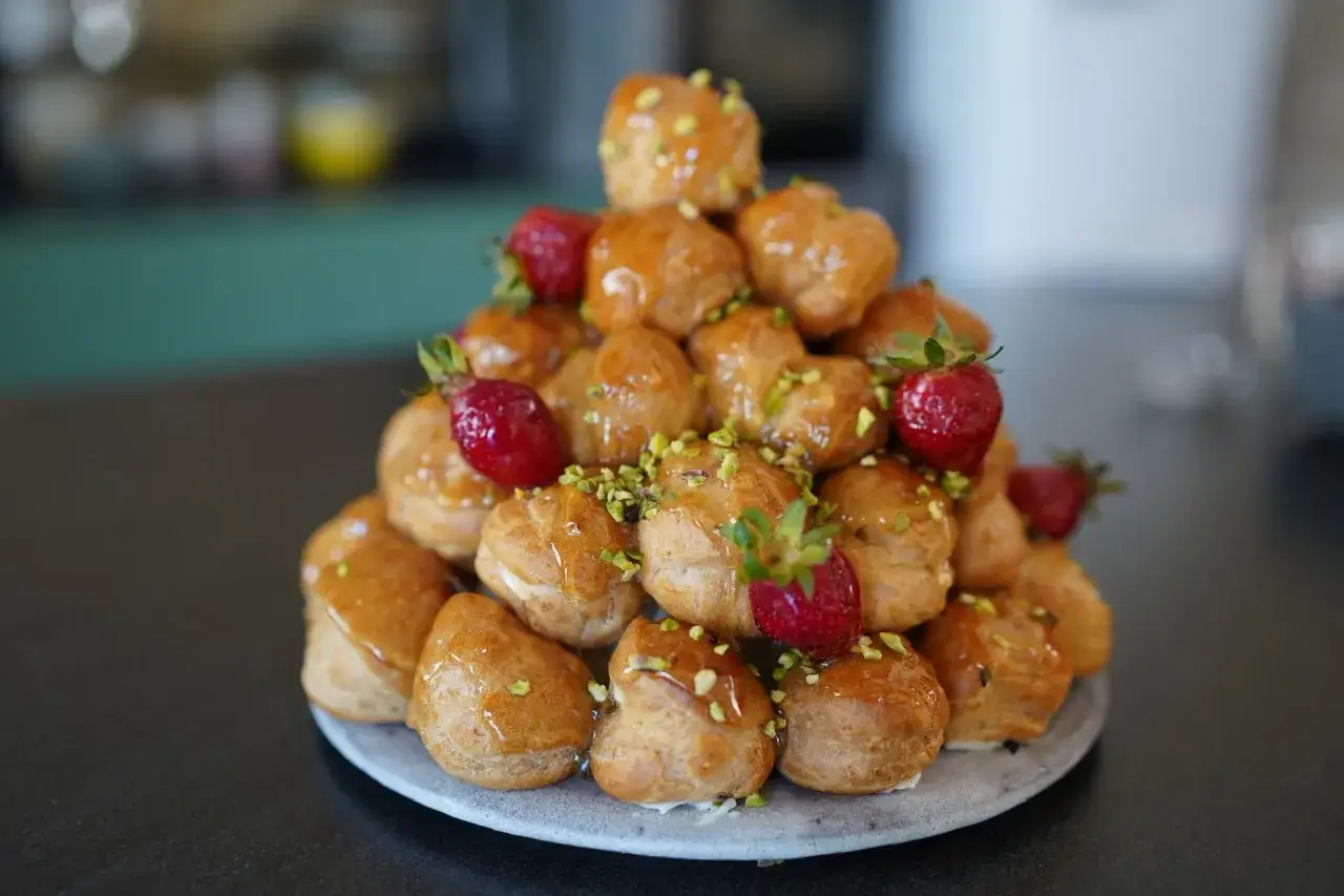 Magnifique chou pièce montée, décorée de fraises et pistaches concassées, un délice gourmand.