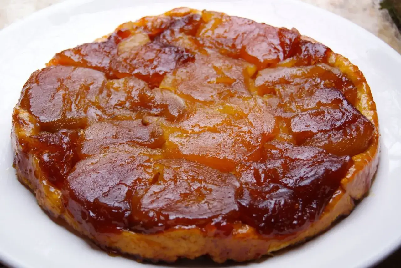 Tarte Tatin caramélisée sur sa pâte brisée dorée, un délice gourmand prêt à être dégusté.