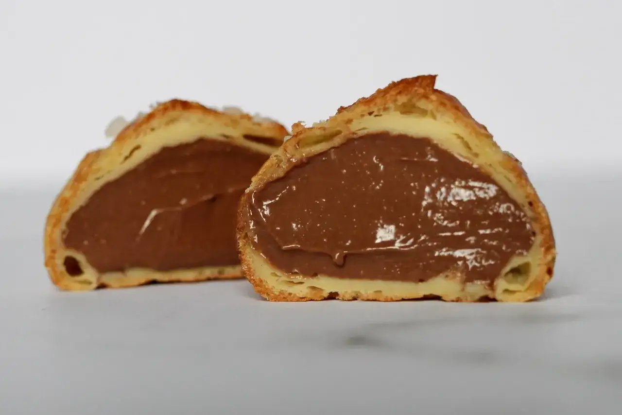 Deux moiti&eacute;s de profiteroles au chocolat, g&eacute;n&eacute;reusement garnies d'une cr&egrave;me onctueuse et brillante.