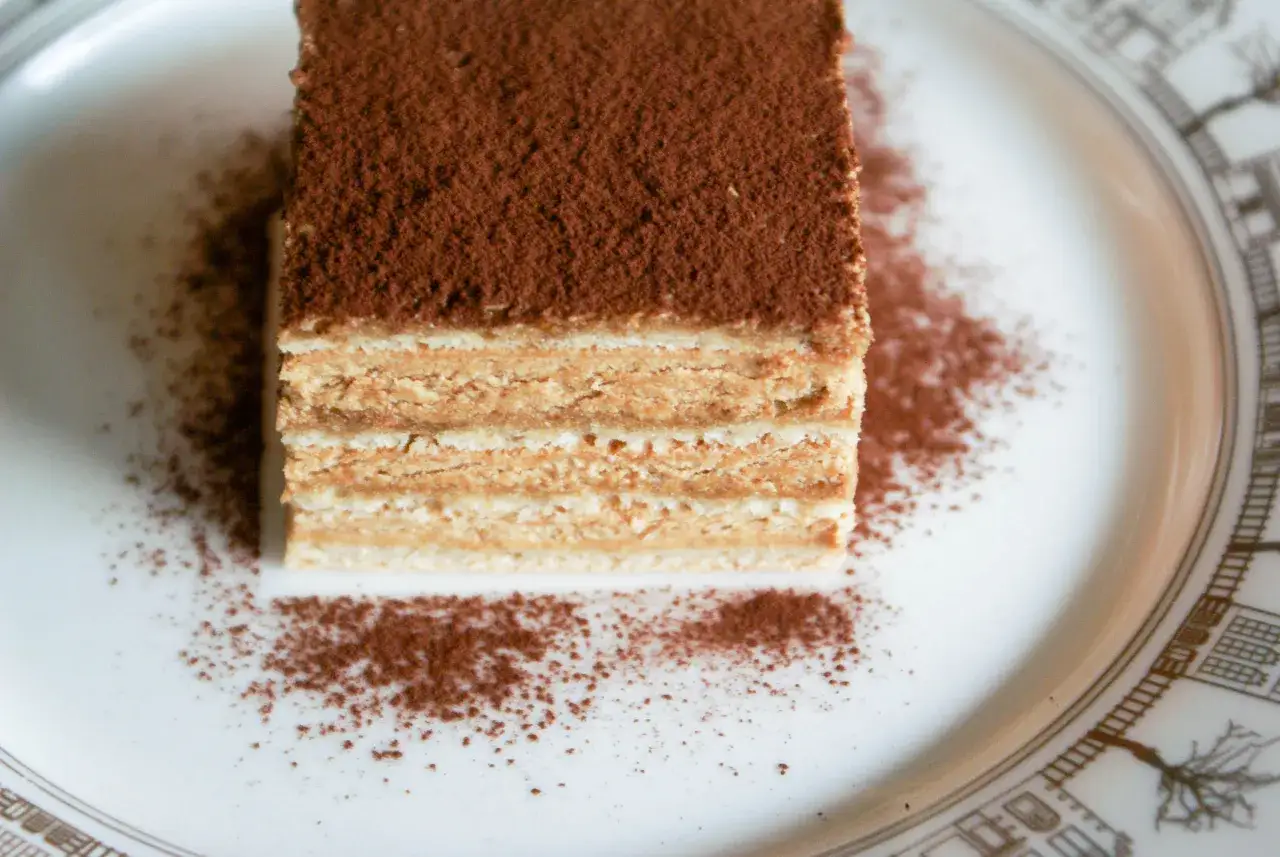 Tranche de gâteau aux couches fines, saupoudrée de cacao. Un délice qui rappelle le moka café.