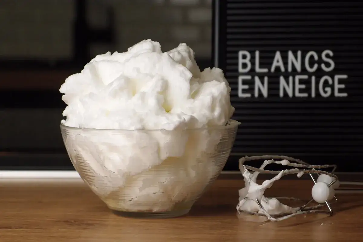 Un bol rempli de blancs en neige aériens, comme un nuage. À côté, un fouet de batteur couvert de cette mousse légère.