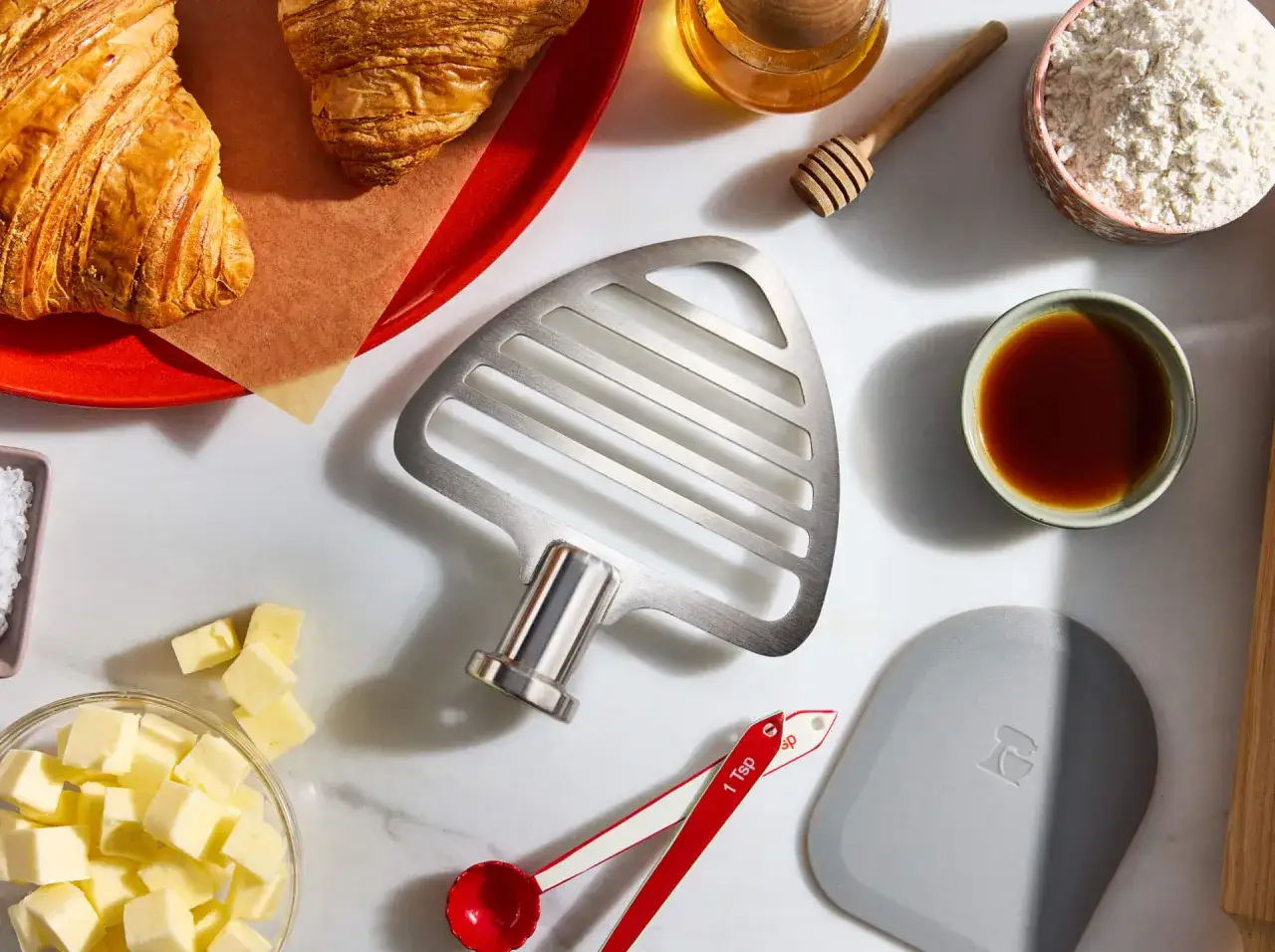 Accessoire de batteur électrique : les crochets servent à pétrir la pâte à pain ou à faire des pâtes lourdes. Ici, des croissants, du beurre, de la farine, du miel et des cuillères doseuses.