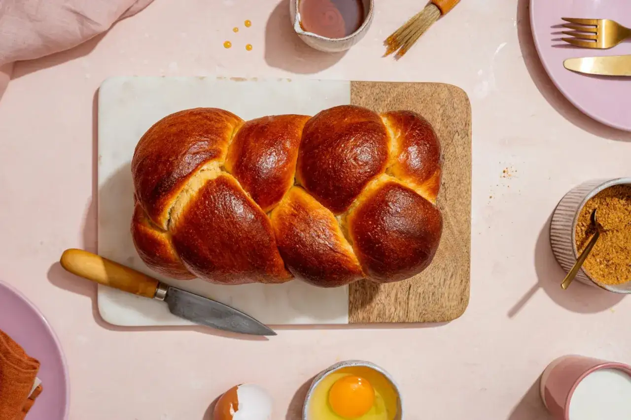 Belle brioche tressée dorée sur planche. Idée pour savoir comment rattraper une pâte à brioche qui ne monte pas : vérifiez la levure et la température.