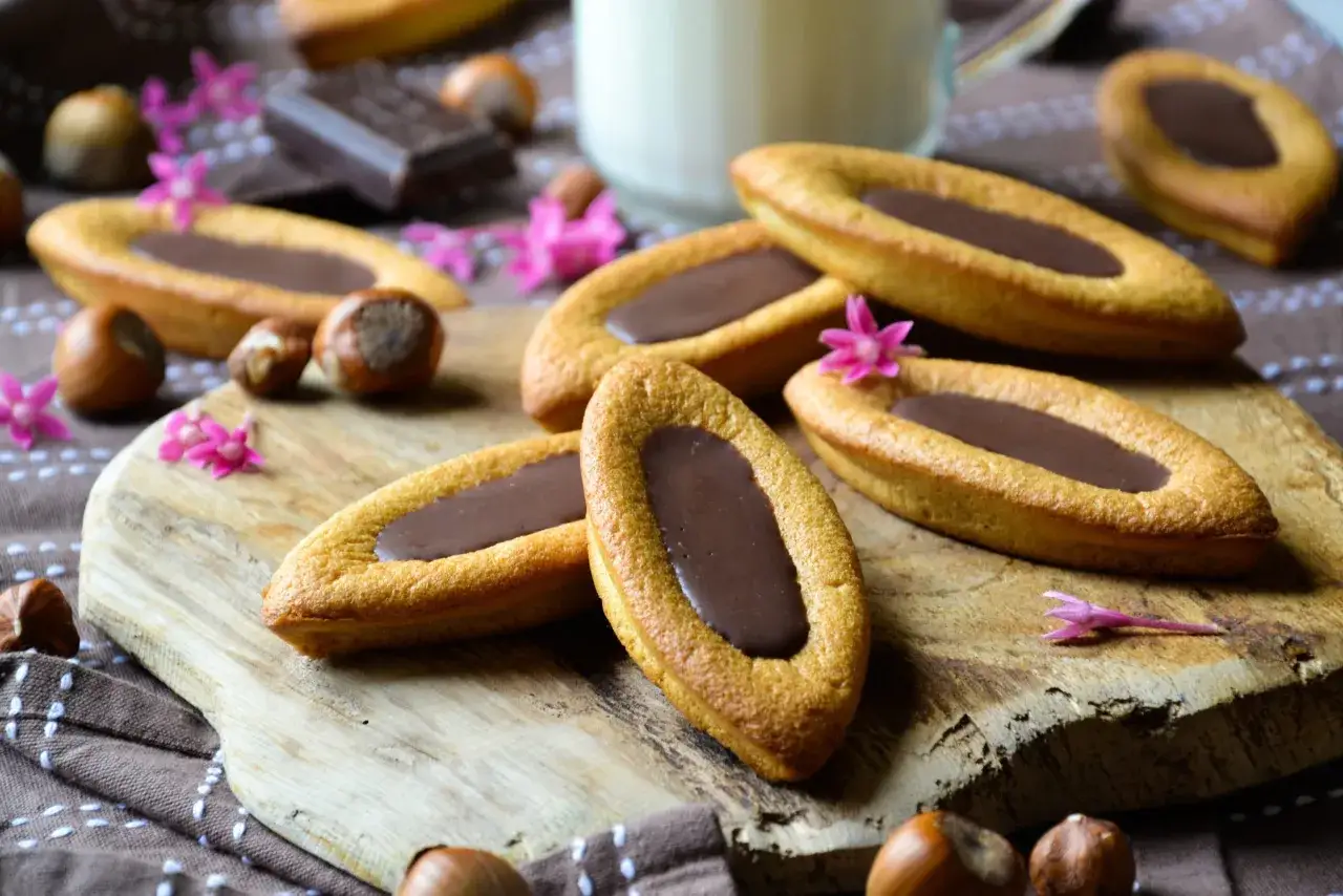 Délicieuses barquettes chocolat, garnies d'une ganache onctueuse, parsemées de noisettes et de fleurs roses. Une invitation à la gourmandise.