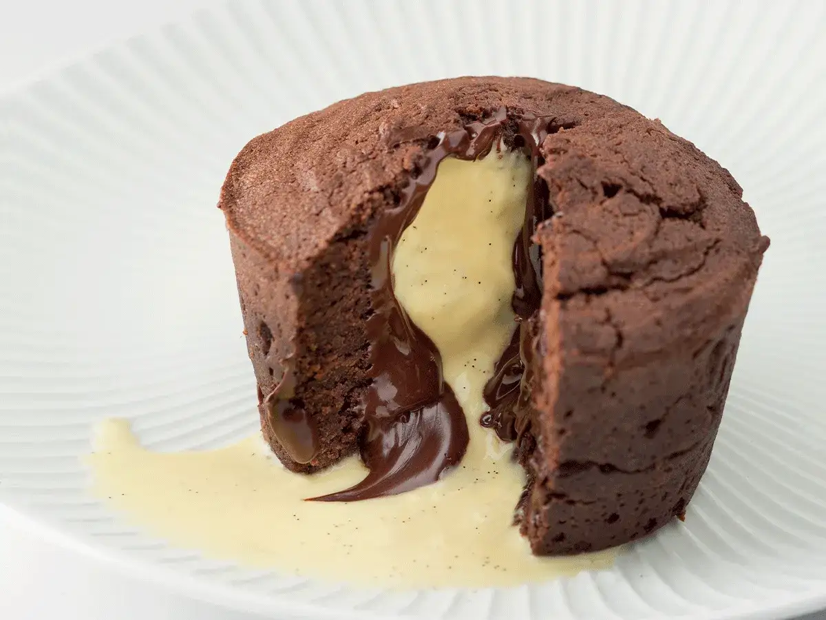 Un délicieux gâteau aux chocolats fondant, avec une crème anglaise à la vanille qui coule.