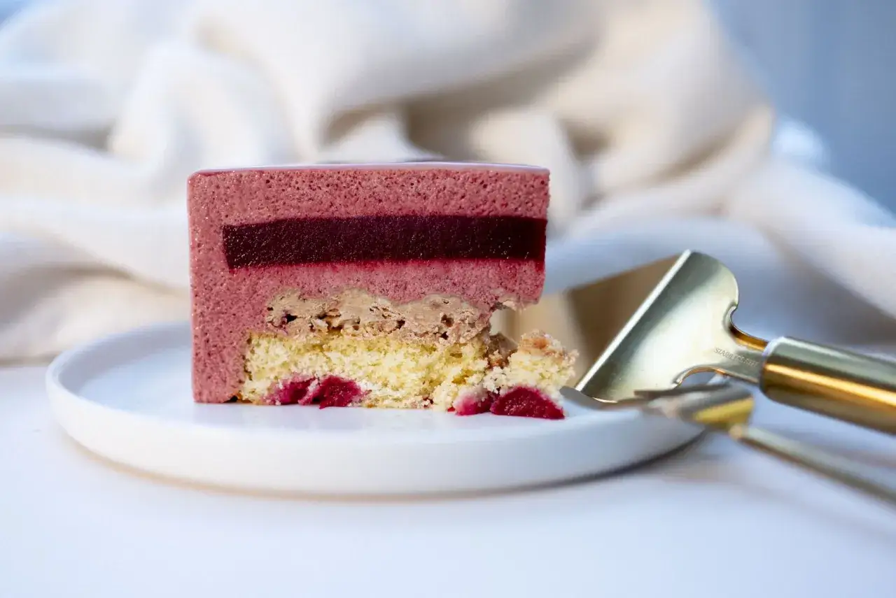 Tranche d'un gâteau aux fruits rouges, parfait pour un cours de pâtisserie en ligne. Une œuvre d'art gourmande.