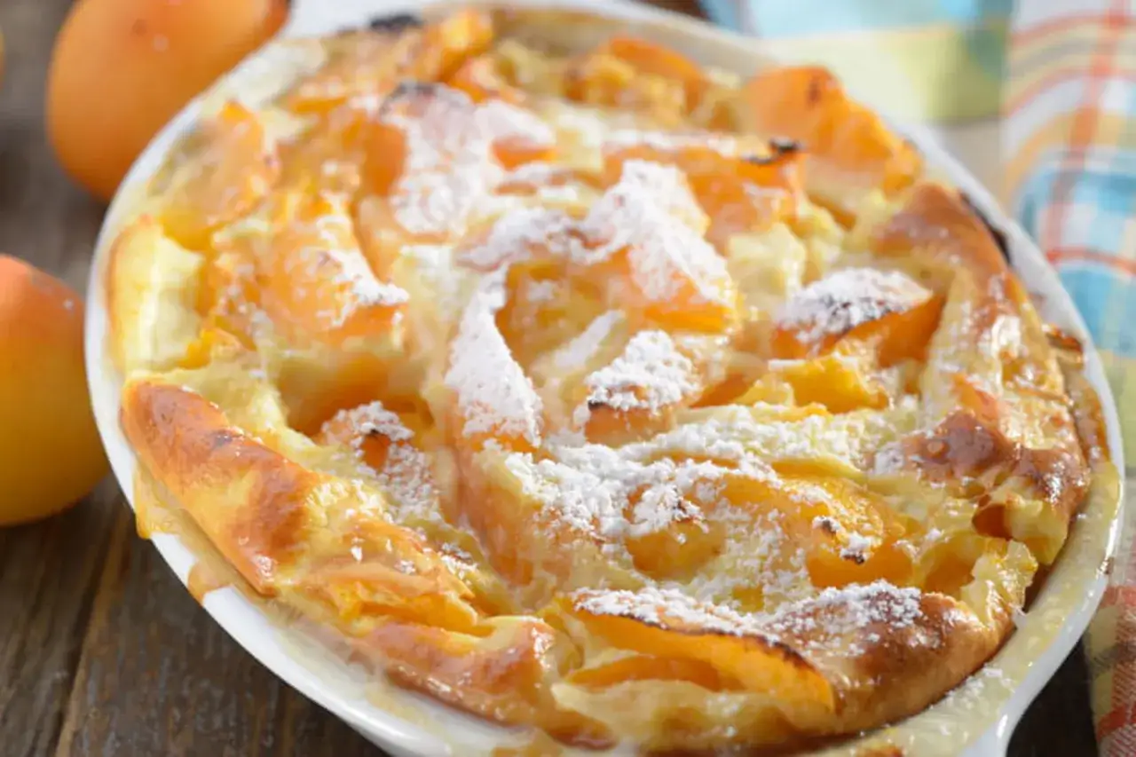Clafoutis abricot chef, un délice doré et saupoudré de sucre glace, prêt à être dégusté.