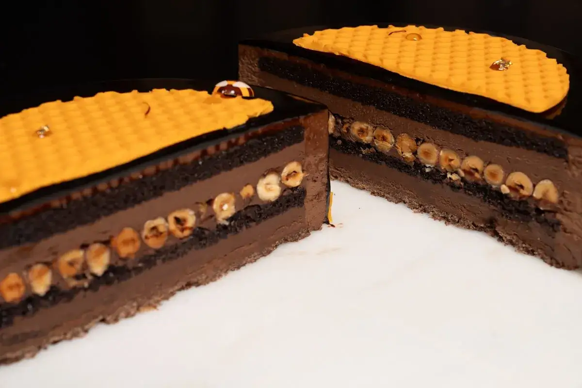 Délicieux entremet chocolat praliné, aux couches généreuses de noisettes croquantes et d'une touche dorée rappelant le miel.