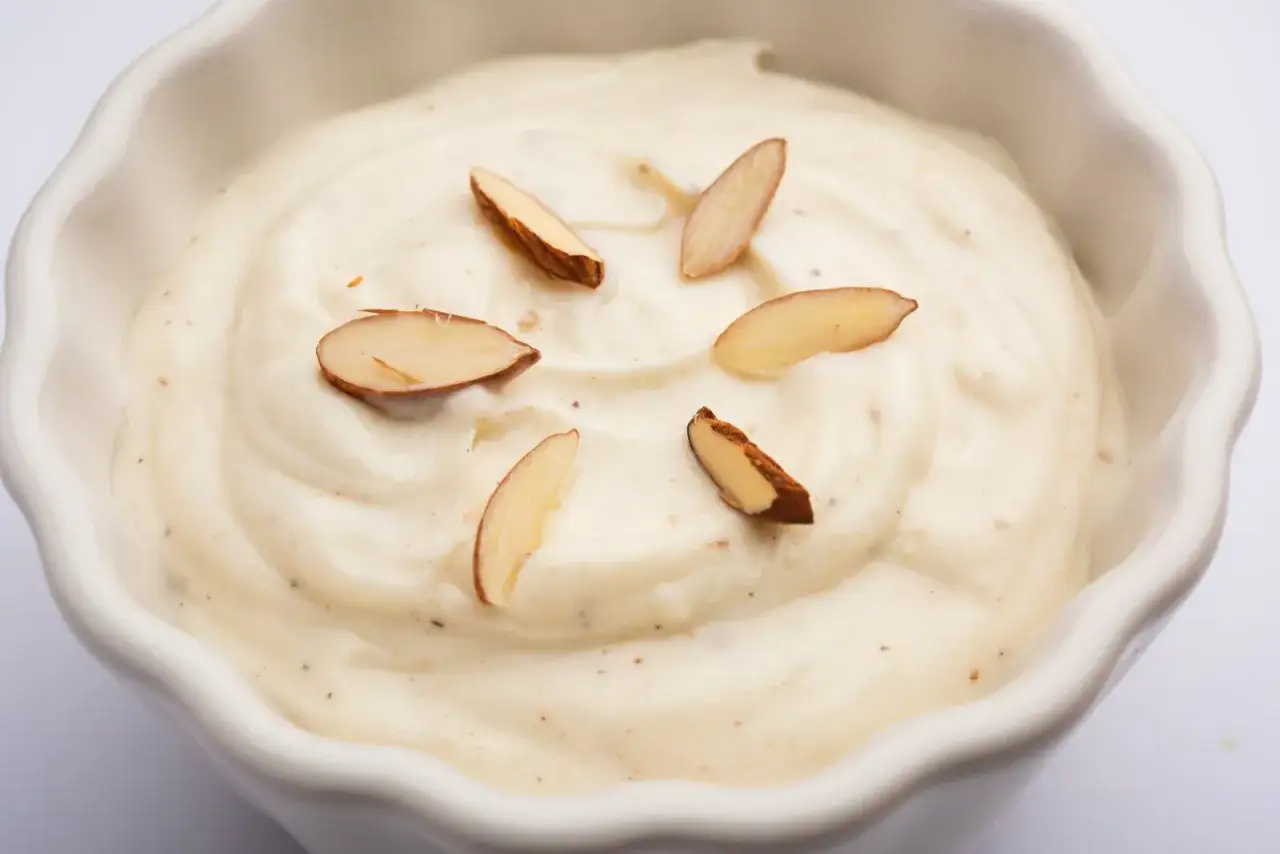 Crème onctueuse à l'amande, parsemée d'éclats d'amandes effilées dans un bol blanc.