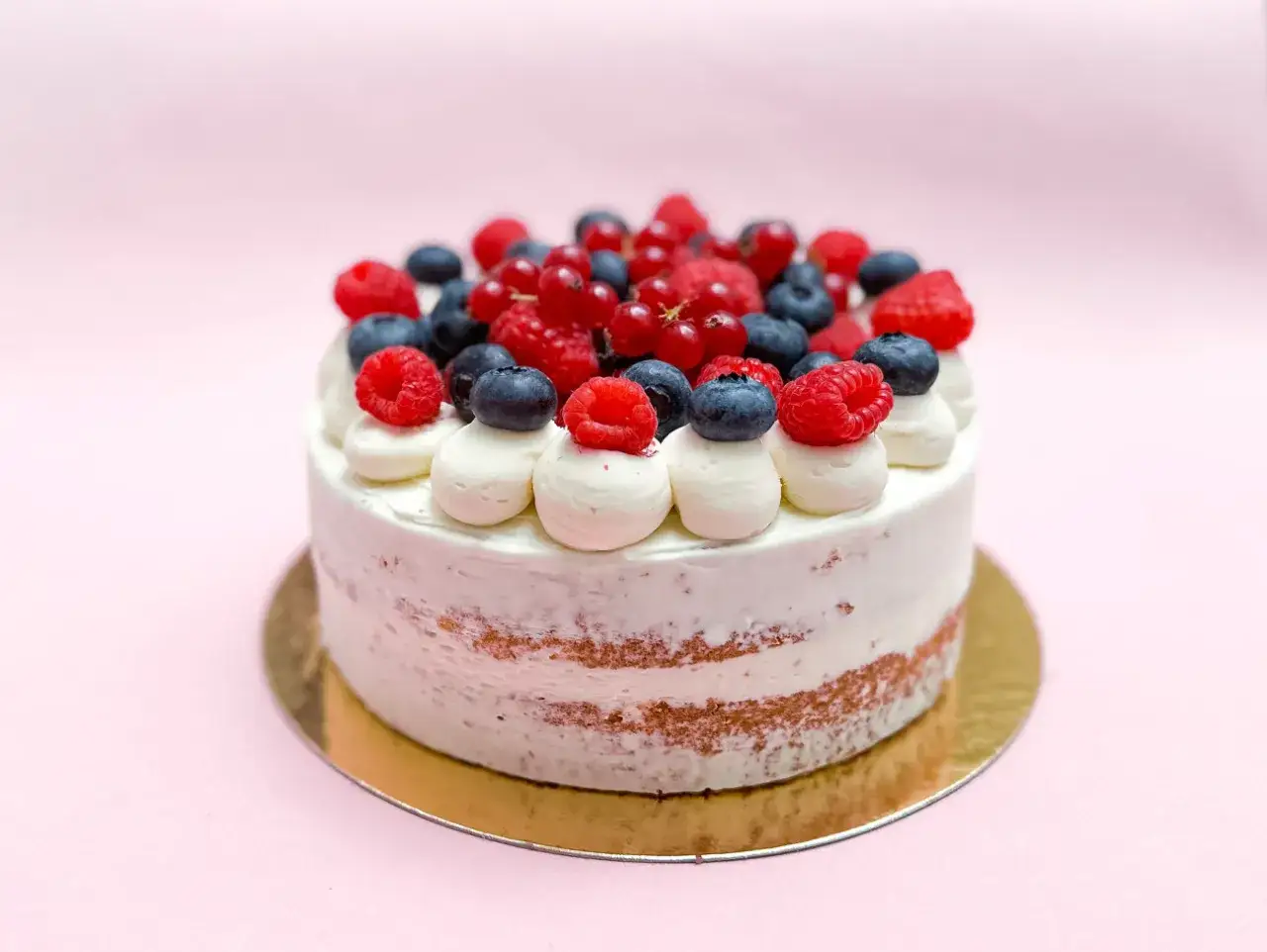Un délicieux layer cake fruit rouge, garni de crème et de baies fraîches, prêt à être dégusté.