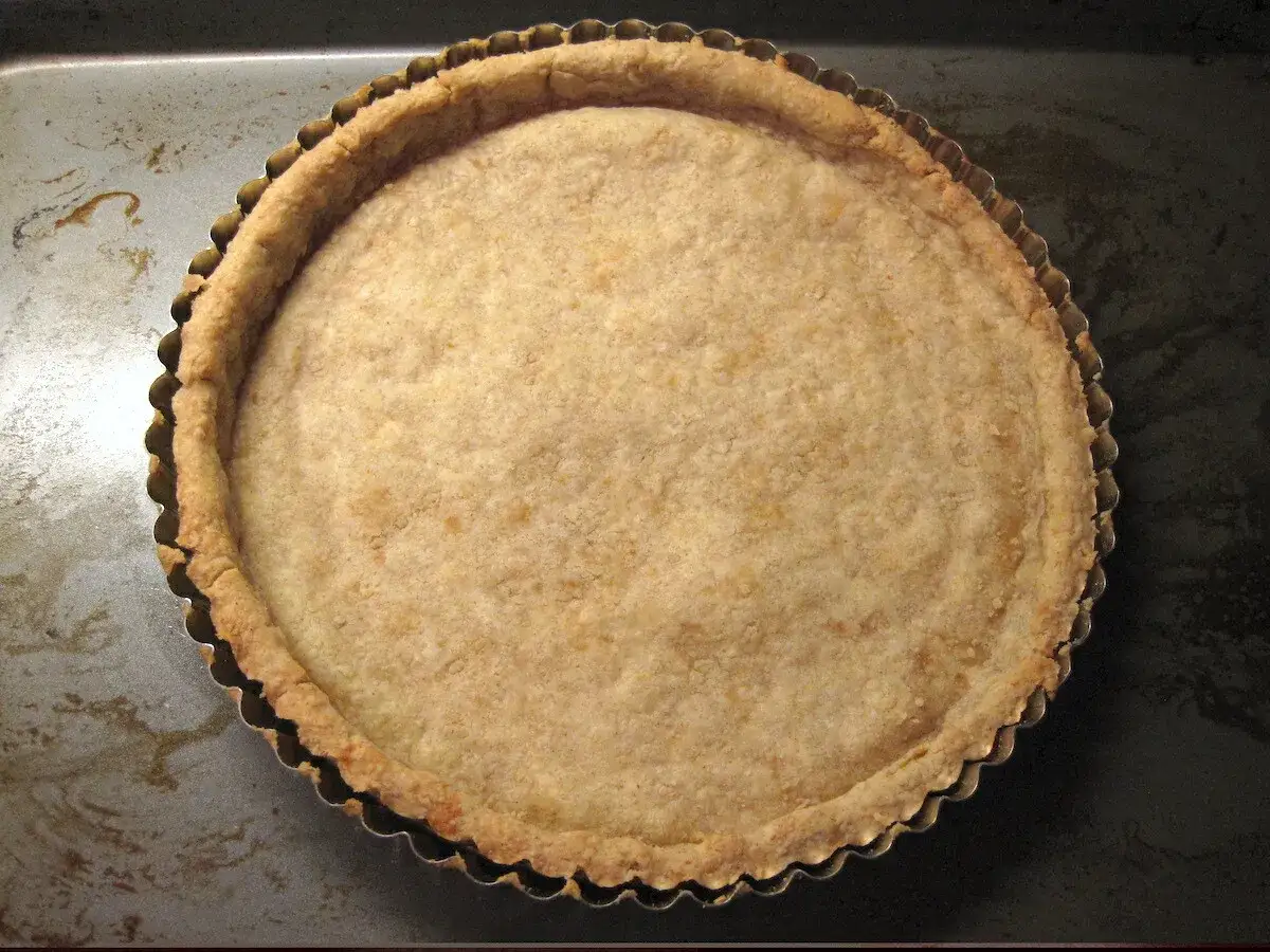 Pâte feuilletée cuite à blanc dans un moule à tarte, prête pour la garniture. Le temps de cuisson est parfait.