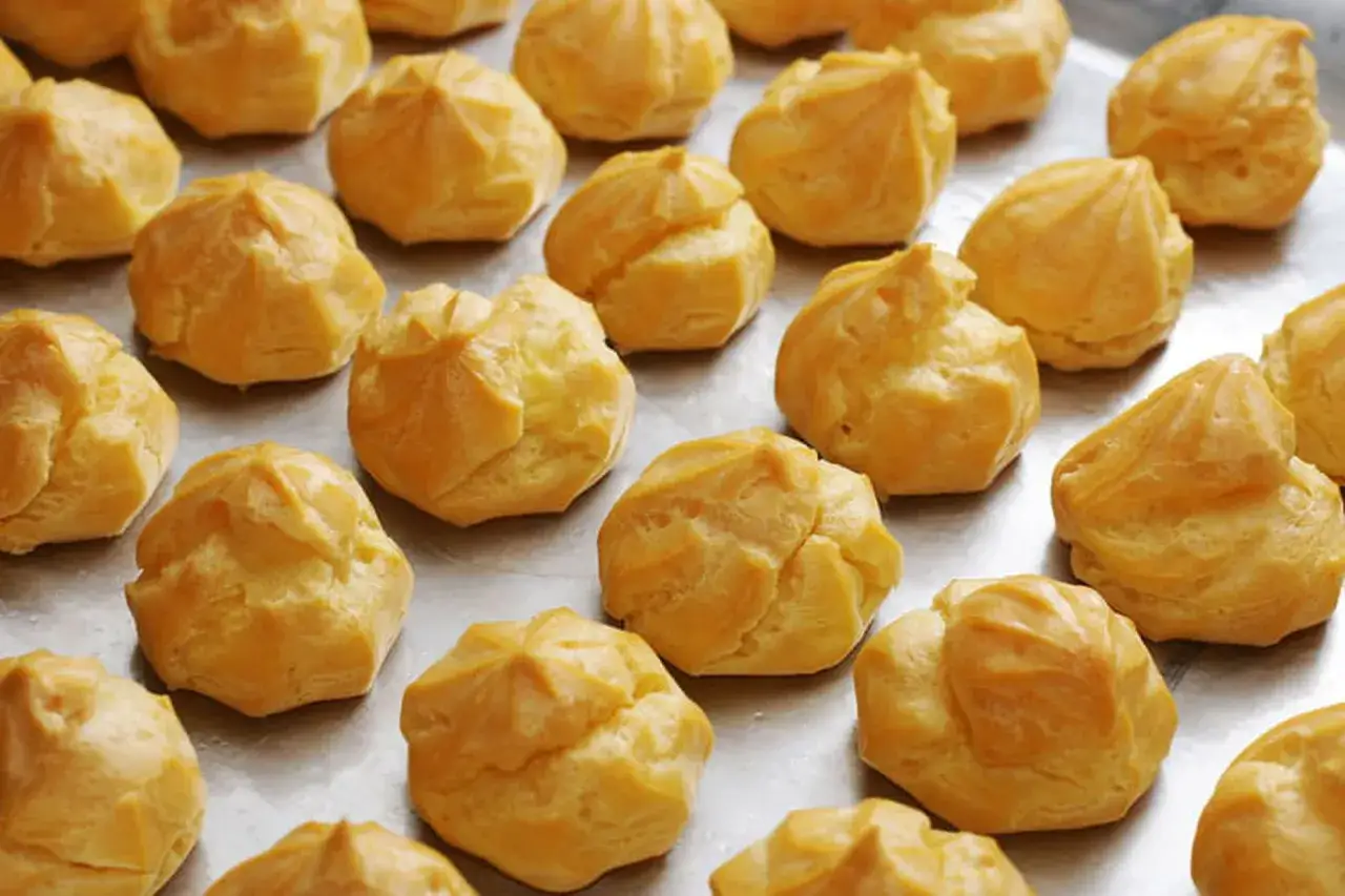Une fournée de choux à la crème dorés et prêts pour la garniture. Ils attendent patiemment leur destin gourmand.