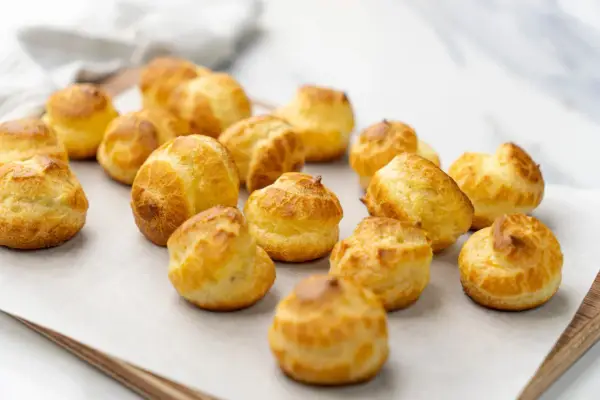 Une douzaine de choux pâtissiers dorés et gonflés, prêts à être dégustés.