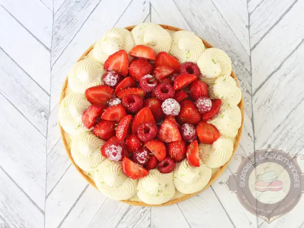 Tarte aux fruits rouges et crème diplomate framboise, décorée de fraises, framboises et zestes de citron vert.