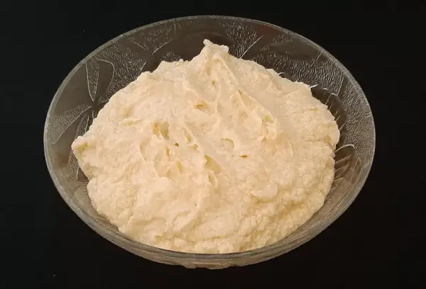 Crème d'amande onctueuse dans un bol en verre texturé, prête à être dégustée.