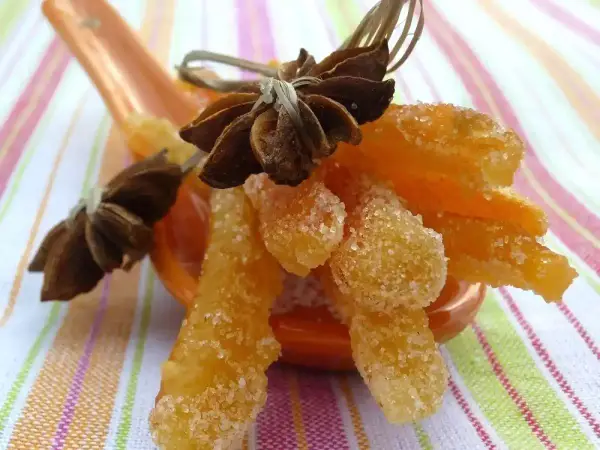 Oranges confites, une recette italienne gourmande, présentées sur une cuillère avec des étoiles de badiane.