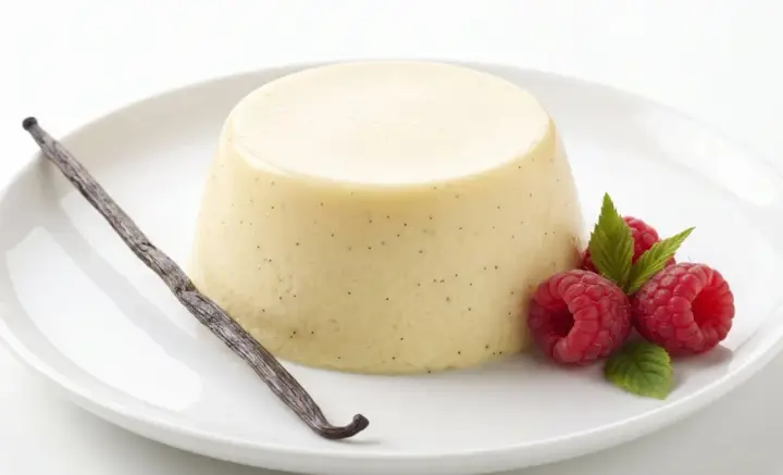Bavaroise vanille on a white plate, garnished with raspberries, mint leaves and a vanilla bean.