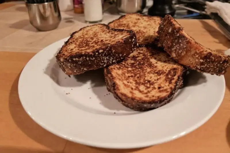 Quatre tranches de pain dur au four, dorées et croustillantes, sur une assiette blanche.